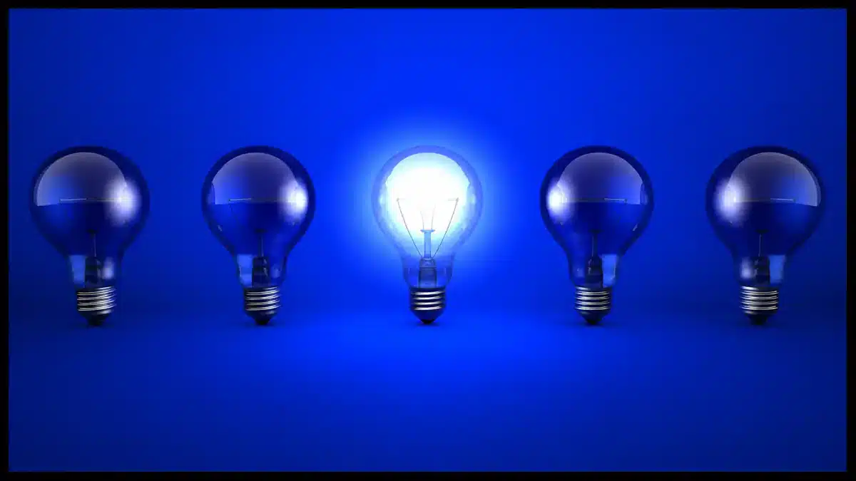 Five blue lightbulbs arranged in a row, with the center bulb glowing brightly.
